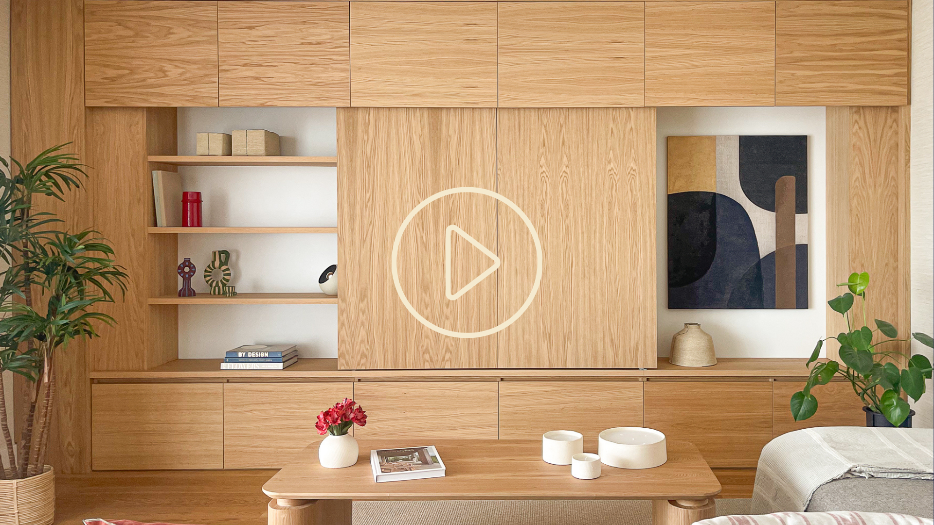 Mueble de salón a medida en madera de roble con puertas correderas y cuadro abstracto.
