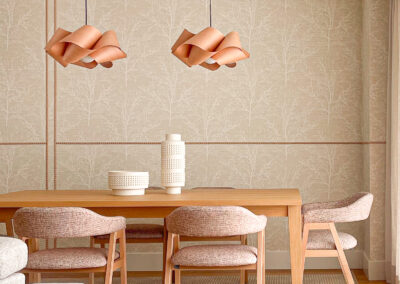 Comedor con mesa de madera, sillas tapizadas y lámparas de madera natural.