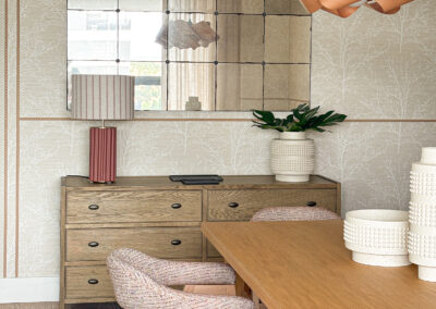 Comedor con cómoda de madera, espejo cuadrícula y decoración en tonos cálidos.