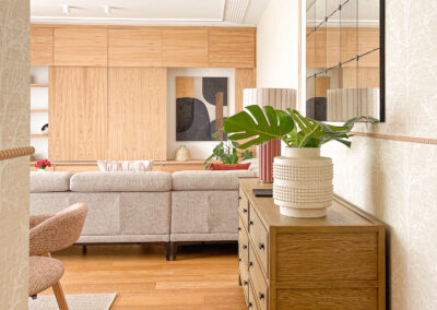 Hall con cómoda de madera, espejo decorativo y vista al salón comedor.