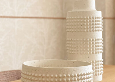 Jarrones decorativos en cerámica blanca con textura sobre mesa de madera.