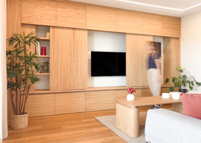 Mueble de TV en madera de roble con puertas correderas y estanterías decorativas.
