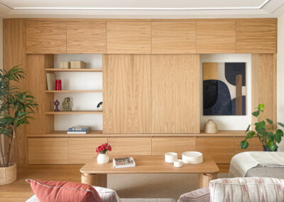 Mueble de salón con estanterías abiertas, puertas correderas y cuadro abstracto integrado.